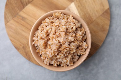 Photo of Tasty wheat porridge in bowl on grey table, top view