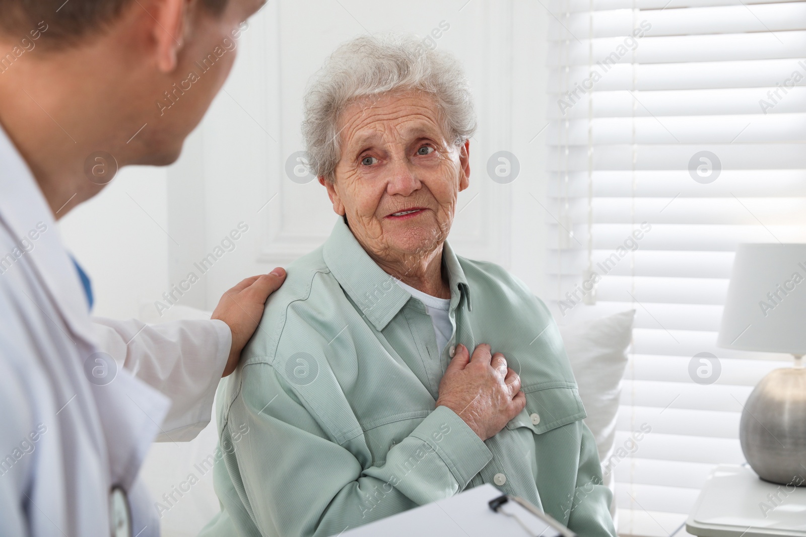 Photo of Caregiver talking to senior woman in living room. Home health care service