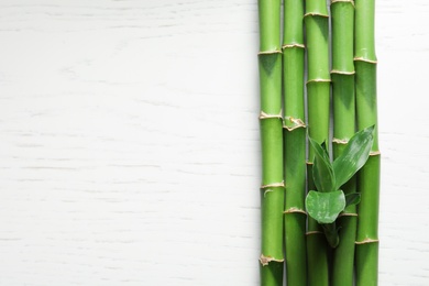 Green bamboo stems and space for text on wooden background, top view