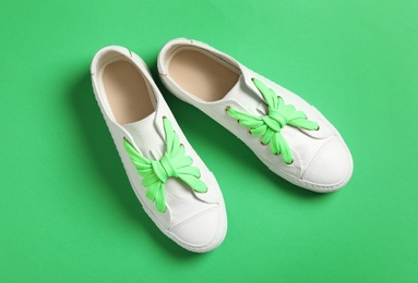 Photo of Stylish sneakers with shoe laces on green background, flat lay