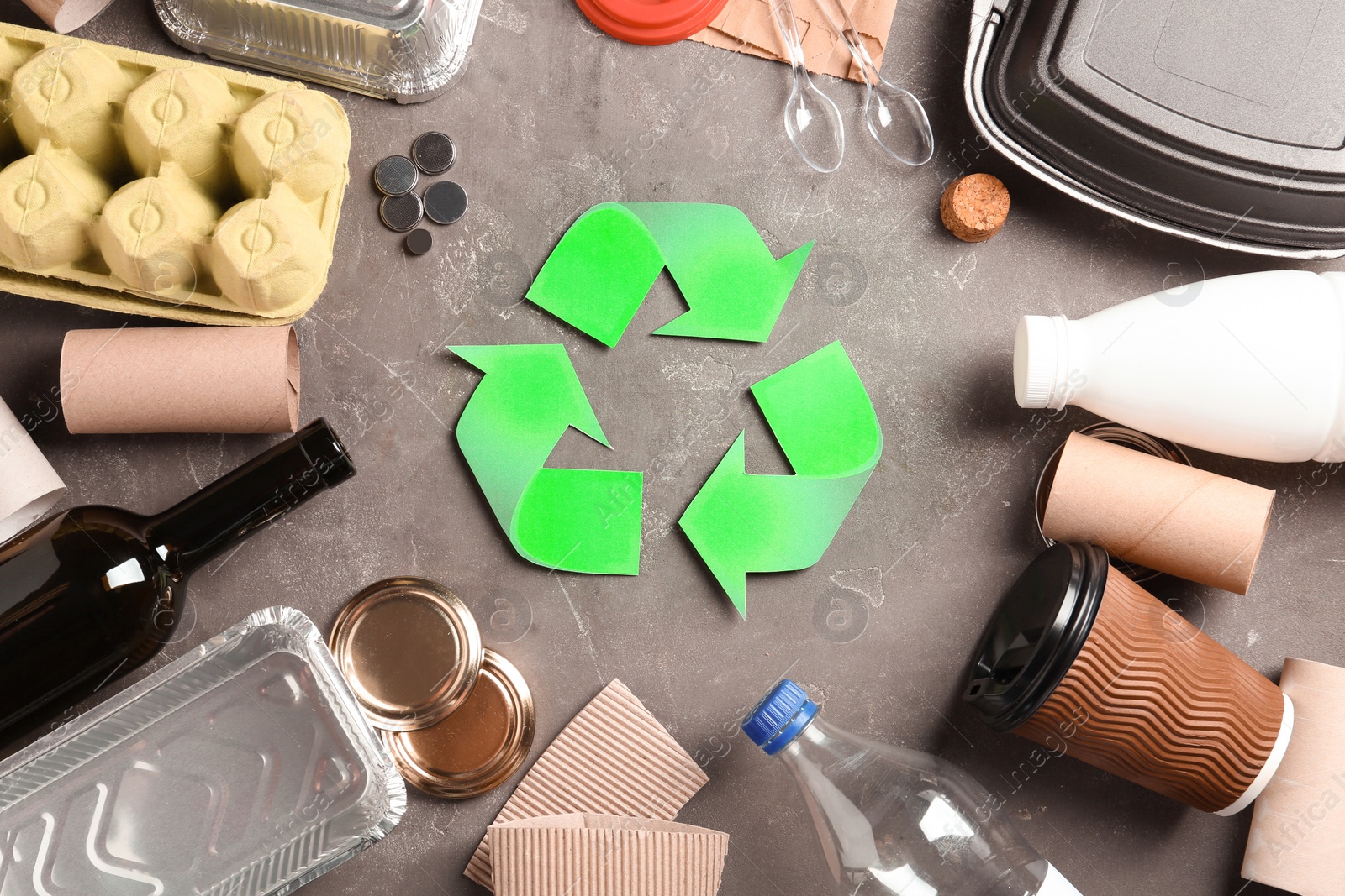 Photo of Recycling symbol and different garbage on gray background, top view