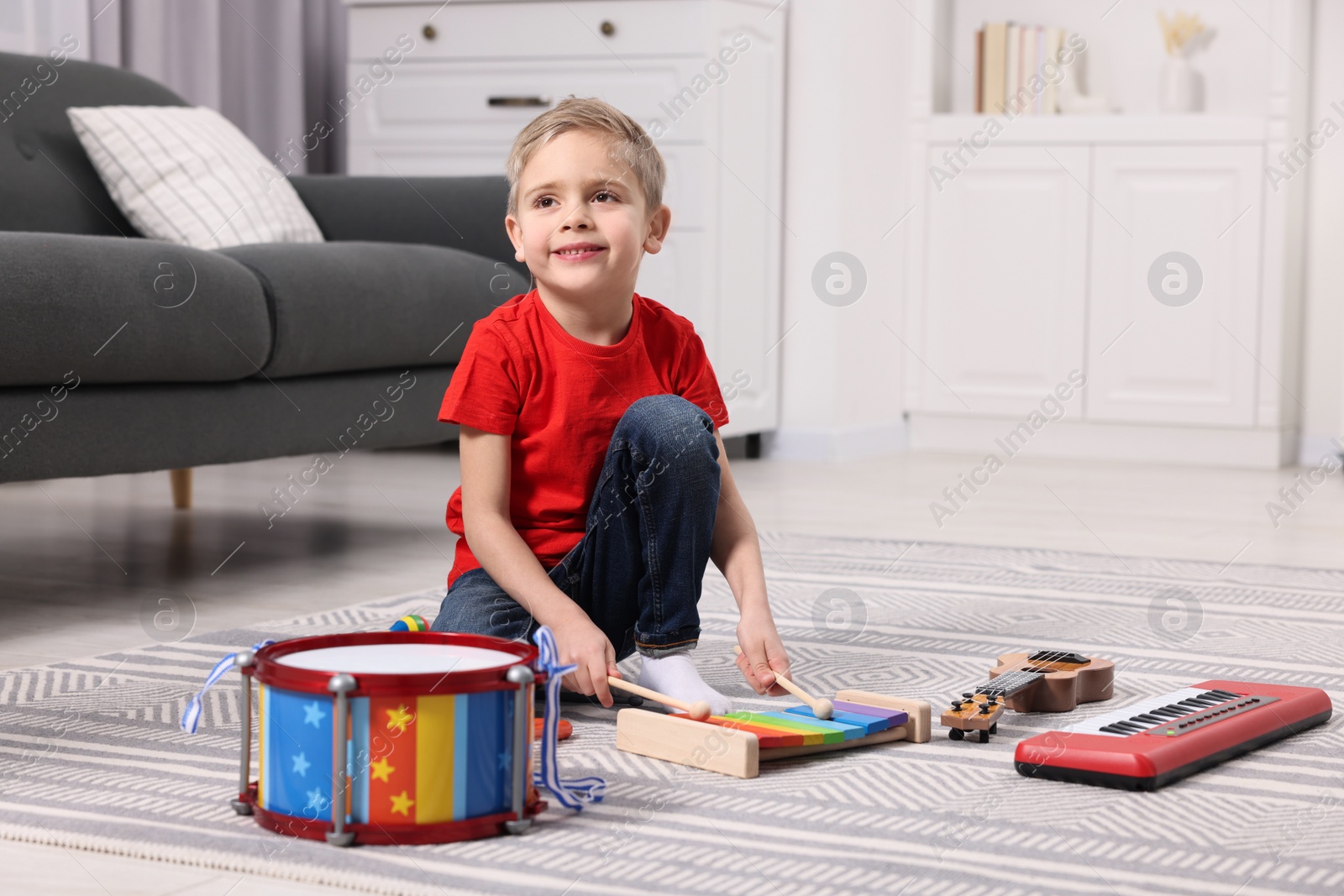 Photo of Little boy playing toy xylophone at home