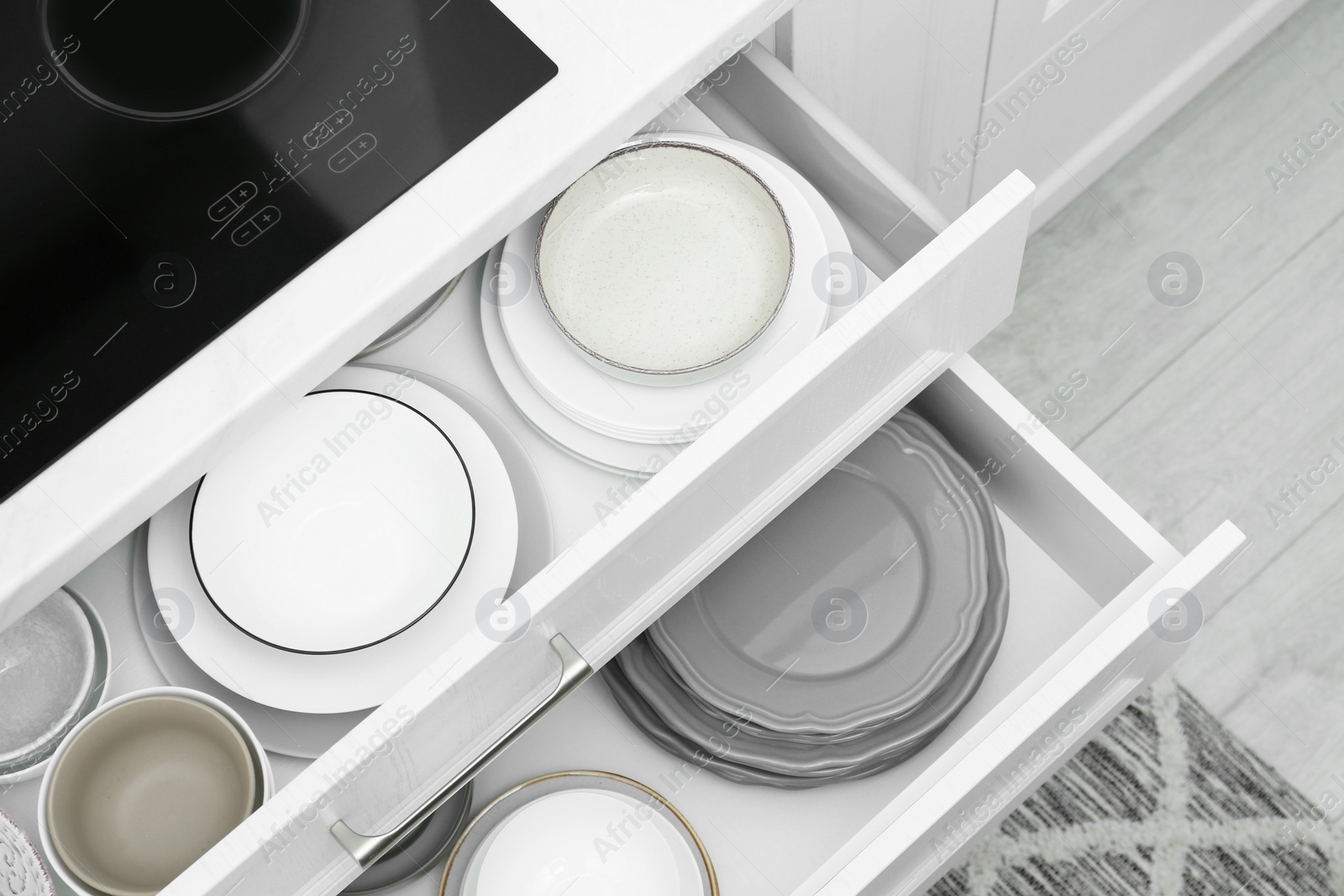 Photo of Open drawers with different plates and bowls in kitchen, above view