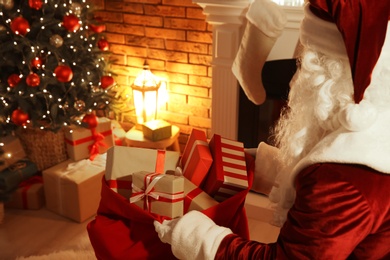 Photo of Santa Claus with sack of gifts in festively decorated room