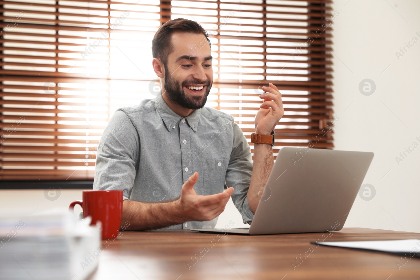 Photo of Man using video chat on laptop in home office