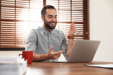 Photo of Man using video chat on laptop in home office