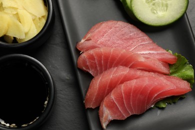 Tasty sashimi (pieces of fresh raw tuna) on black table, flat lay