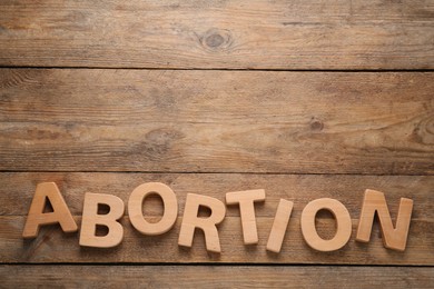 Photo of Word Abortion made of letters on wooden background, flat lay. Space for text
