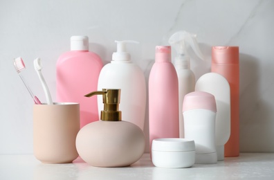 Stick deodorant and different toiletry on marble table near light wall