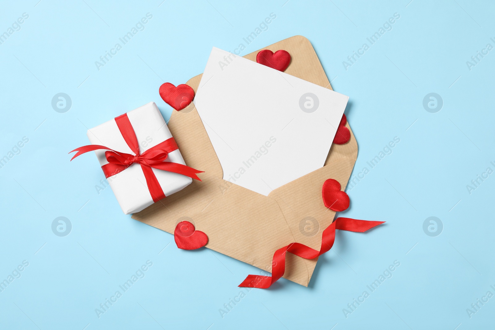 Photo of Flat lay composition with blank card on light blue background, space for text. Valentine's Day celebration