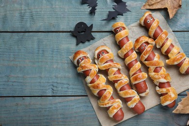 Photo of Cute sausage mummies served on blue wooden table, flat lay with space for text. Halloween party food