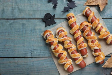 Cute sausage mummies served on blue wooden table, flat lay with space for text. Halloween party food