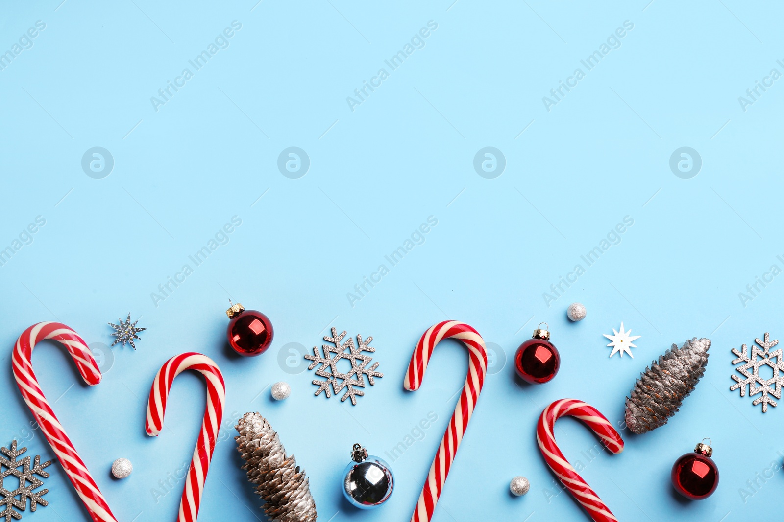 Photo of Flat lay composition with candy canes and Christmas decor on light blue background. Space for text