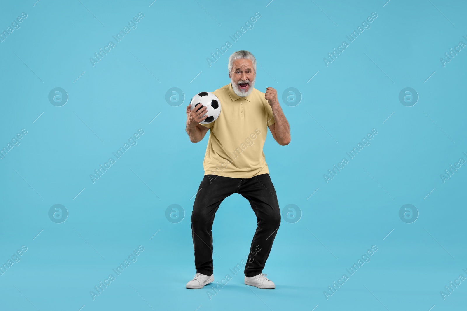 Photo of Happy senior sports fan with soccer ball on light blue background