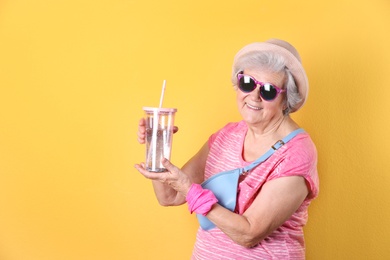 Photo of Portrait of cool grandmother with drink on color background, space for text