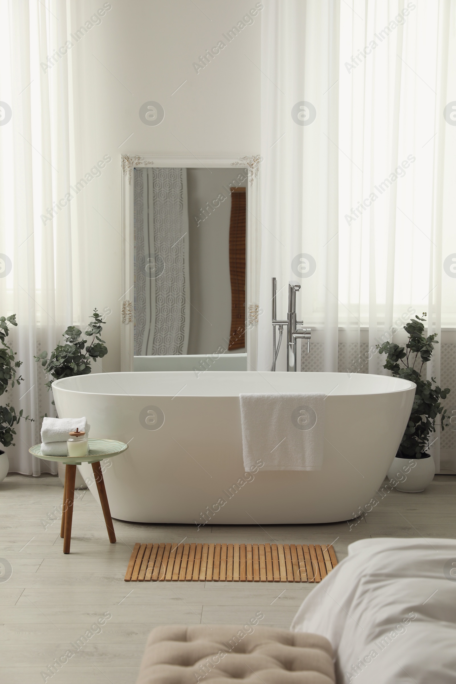 Photo of White tub and decor in light room. Interior design