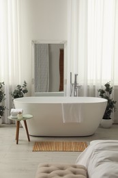 Photo of White tub and decor in light room. Interior design