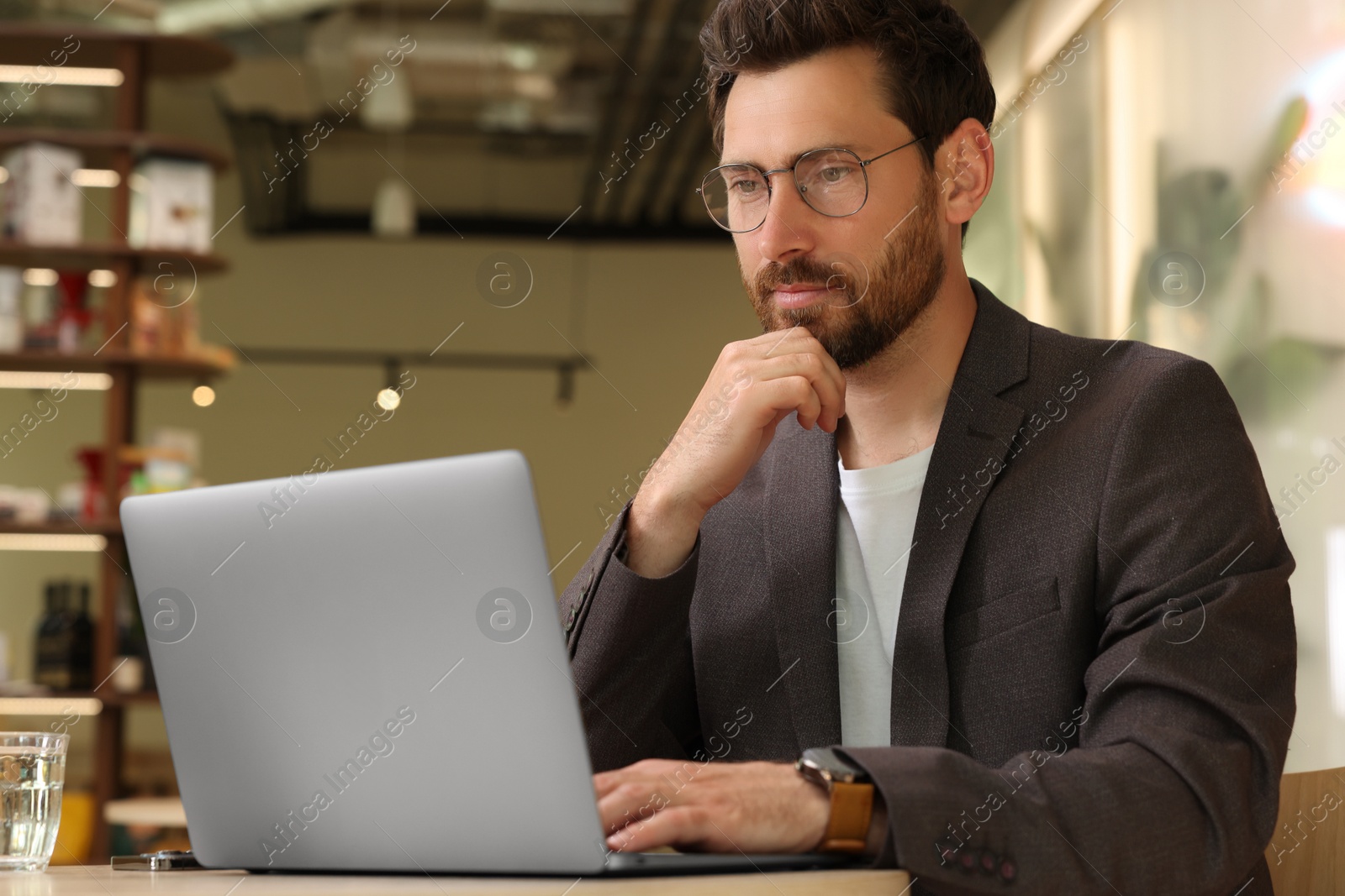 Photo of Man working on laptop at table in cafe