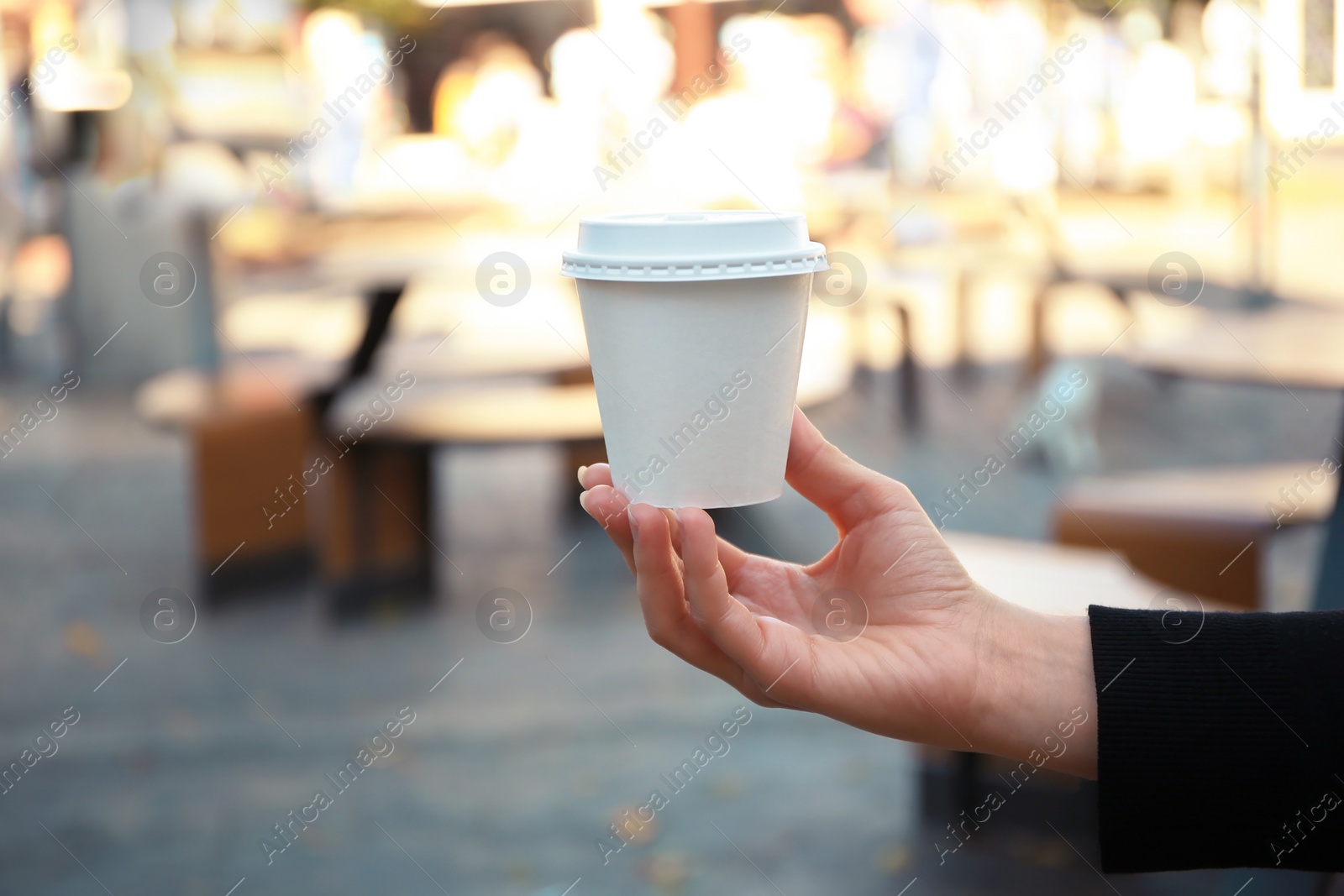 Photo of Woman holding cardboard cup with coffee on city street, closeup. Space for text