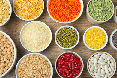 Photo of Different grains and cereals on wooden table, flat lay