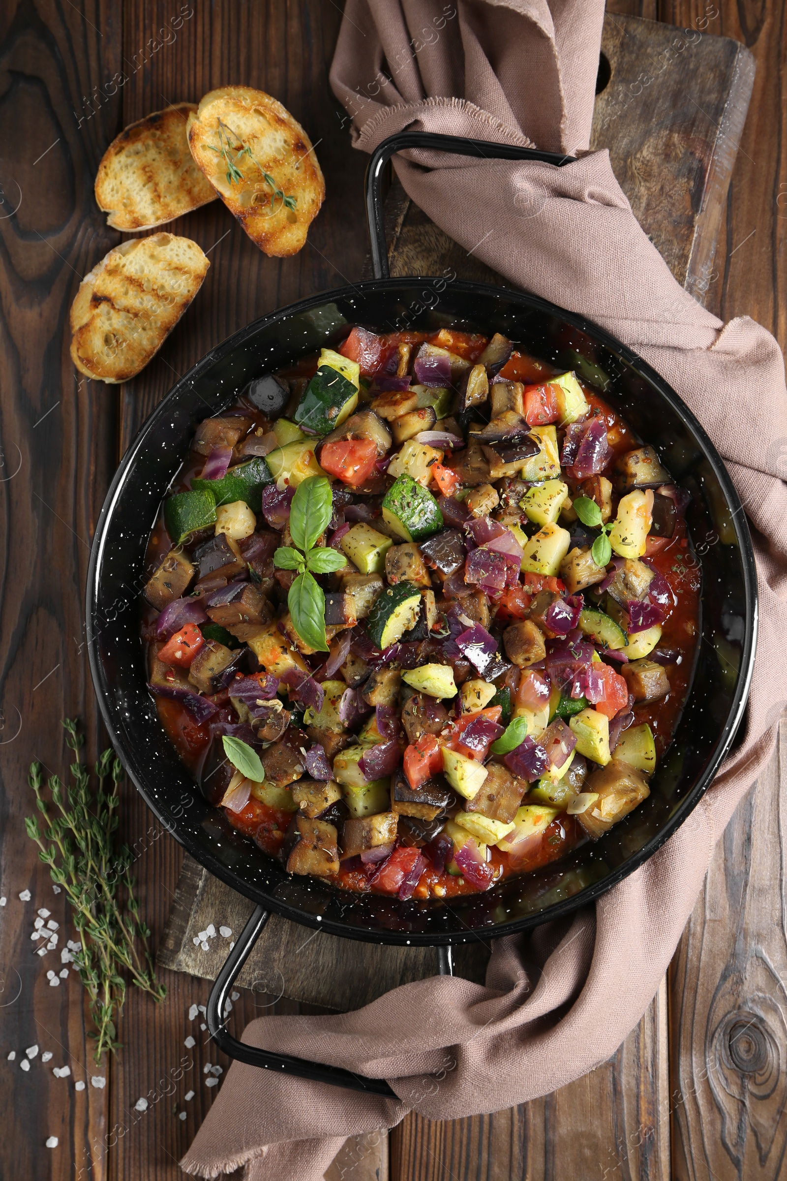 Photo of Delicious ratatouille in baking dish served on wooden table, flat lay