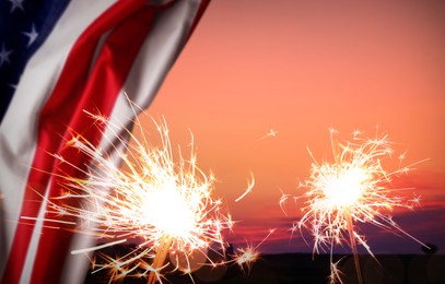 Image of 4th of July - Independence Day of USA. Burning sparkler and American flag outdoors