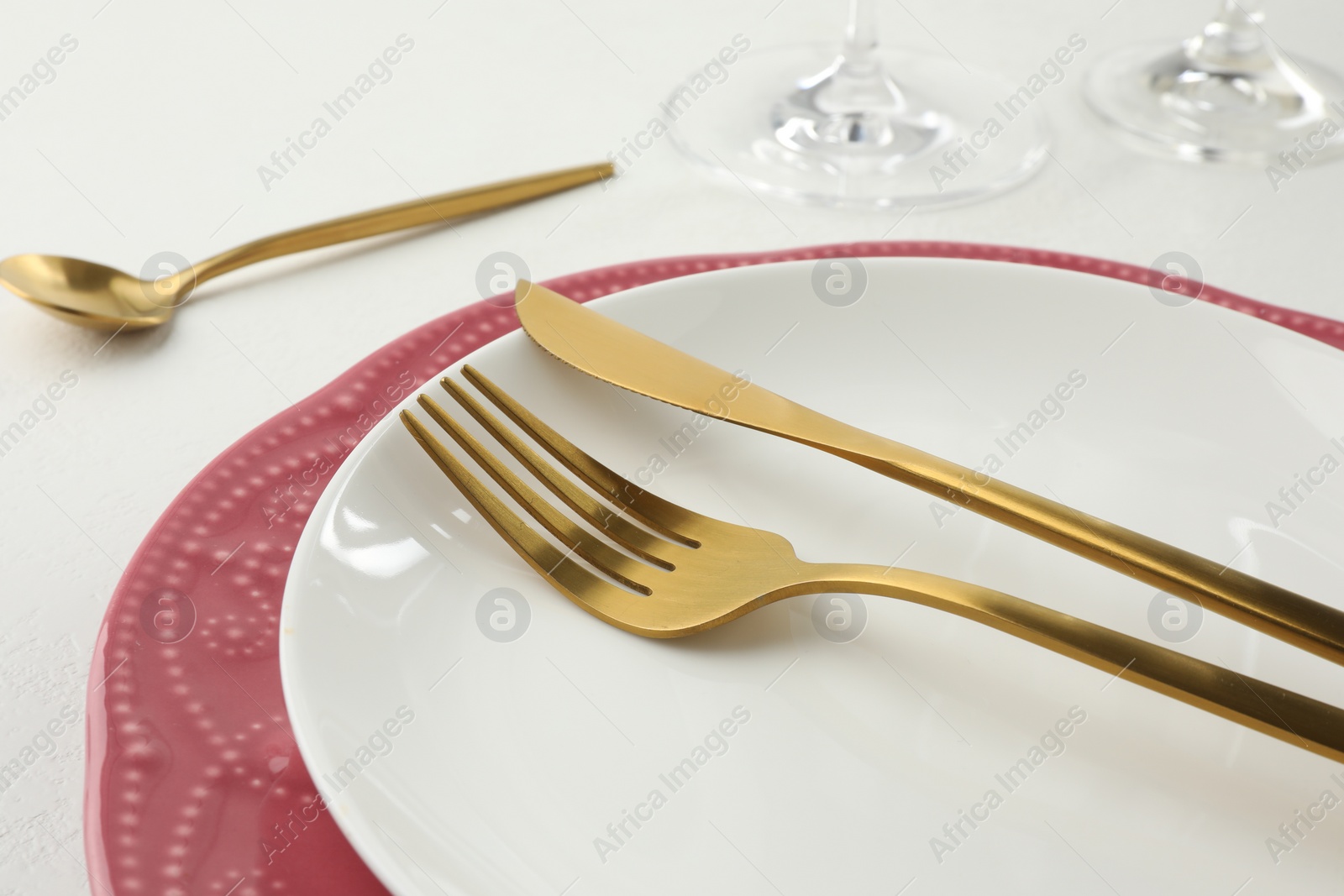 Photo of Stylish setting with cutlery and plates on white textured table, closeup