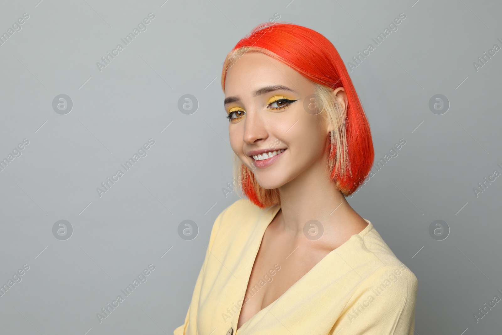 Photo of Beautiful young woman with bright dyed hair on light grey background, space for text