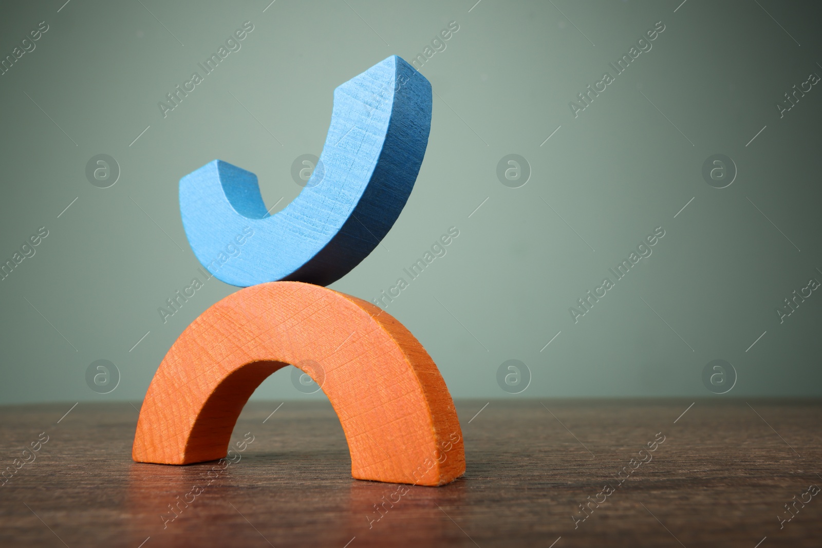 Photo of Colorful wooden pieces of educational toy on table against grey wall, low angle view and space for text. Motor skills development