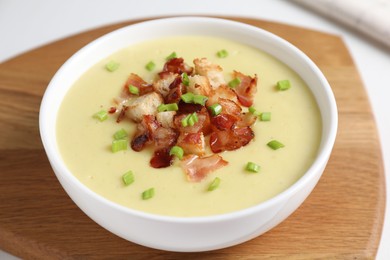 Photo of Tasty potato soup with bacon, green onion and croutons in bowl on white table, closeup