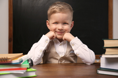 Photo of Cute little child at desk in classroom. First time at school