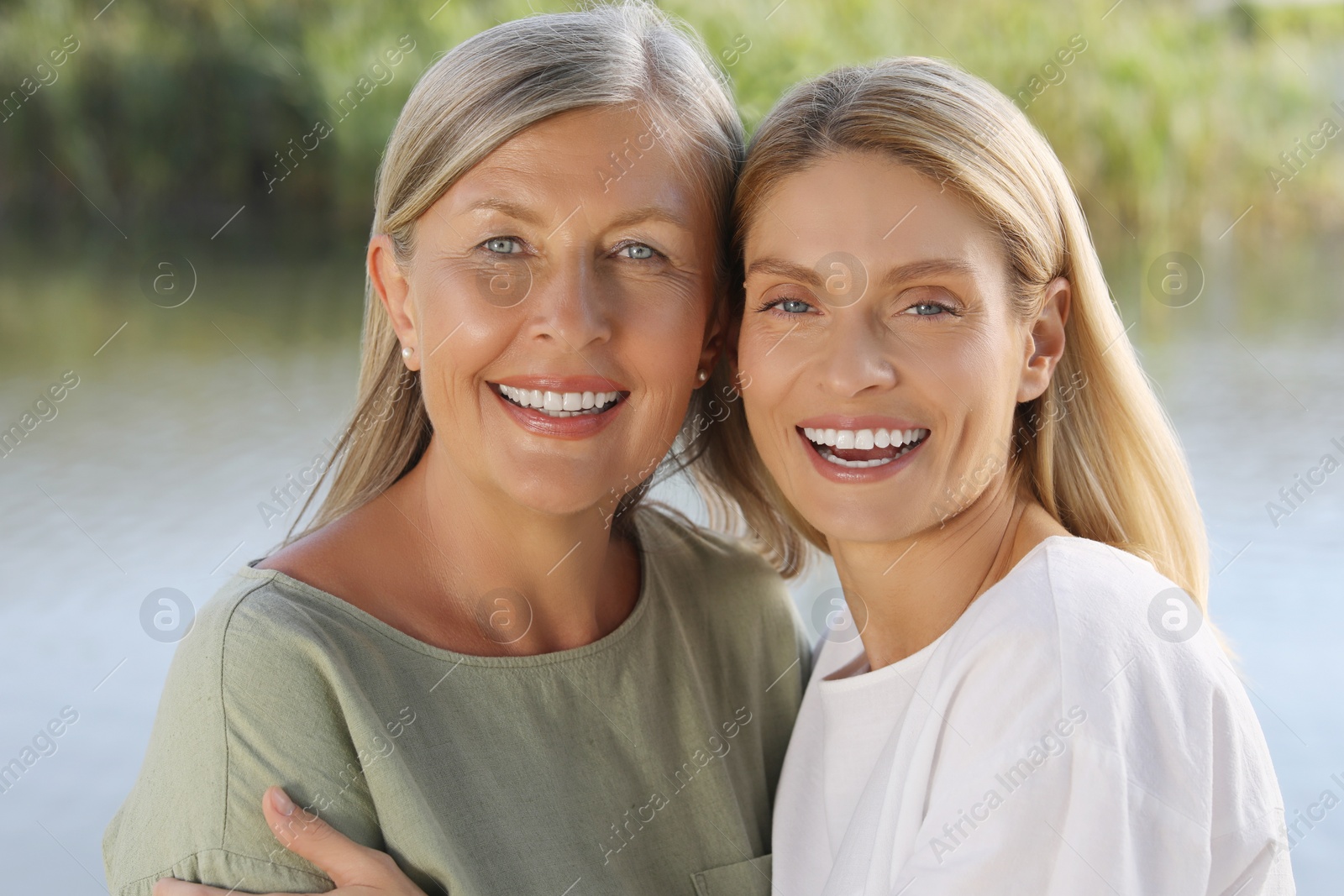 Photo of Family portrait of happy mother and daughter spending time together near pond