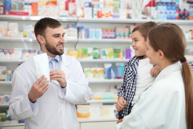 Professional pharmacist working with customer in modern drugstore