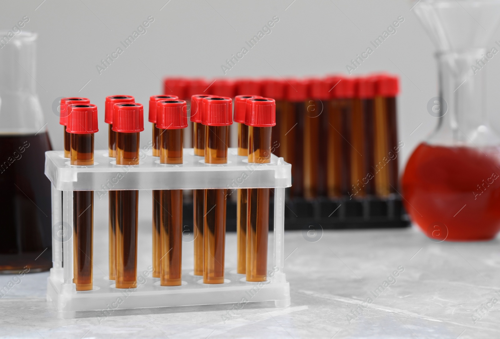 Photo of Different laboratory glassware with brown liquids on white table. Space for text