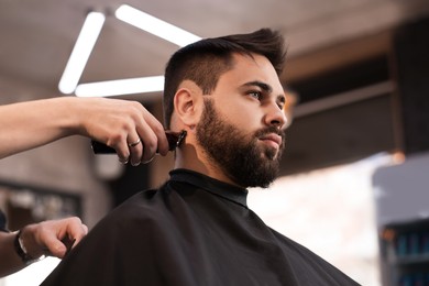 Photo of Professional hairdresser working with client in barbershop, low angle view