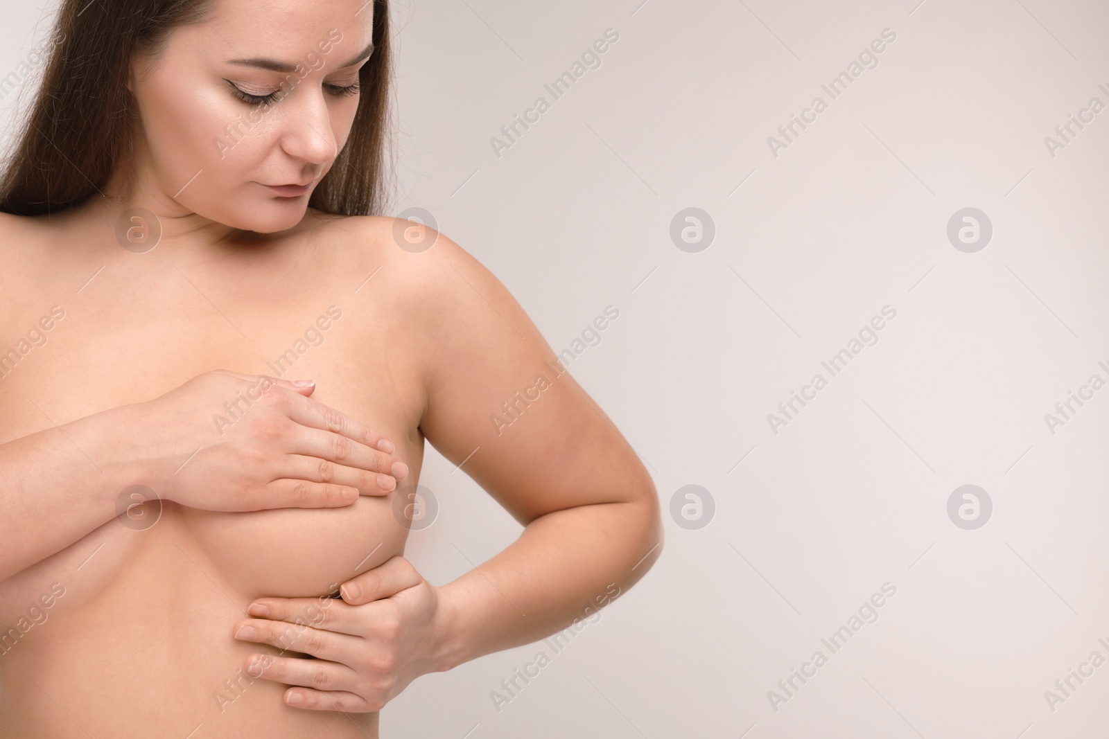 Photo of Mammology. Naked woman doing breast self-examination on light grey background, space for text