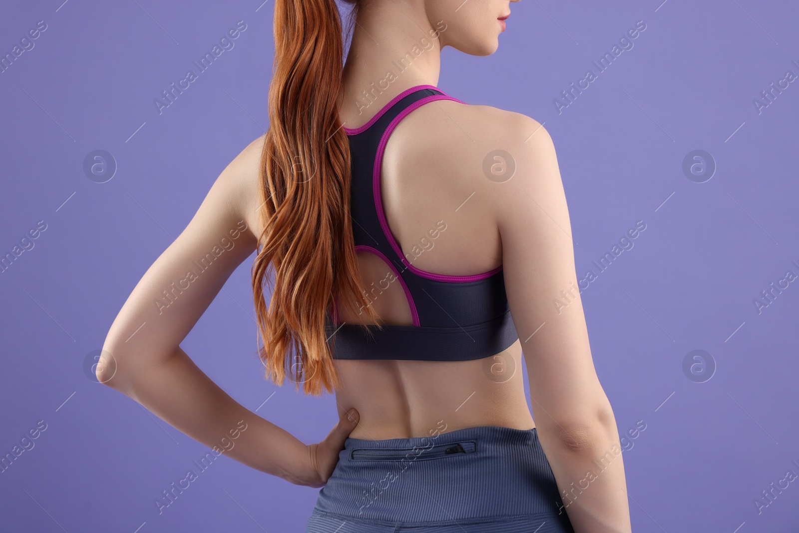 Photo of Woman wearing sportswear on violet background, back view