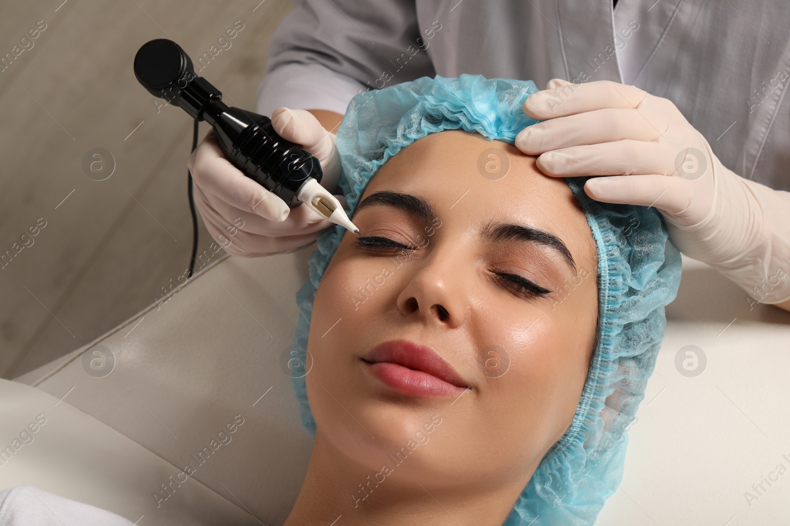 Photo of Young woman undergoing procedure of permanent eyeliner makeup, closeup