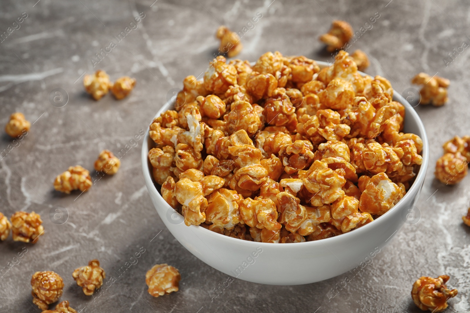 Photo of Delicious popcorn with caramel in bowl on table