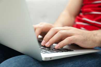 Photo of Man working on modern laptop at home, closeup