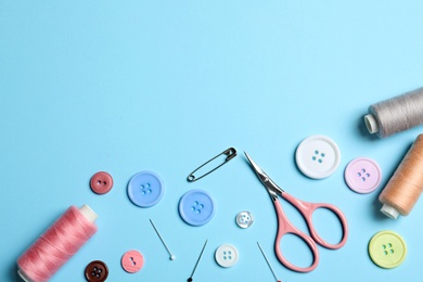 Photo of Flat lay composition with scissors and other sewing accessories on light blue background. Space for text