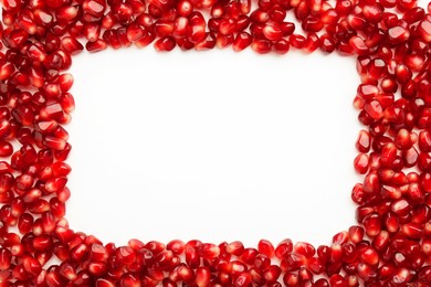 Frame made of ripe juicy pomegranate grains on white background, top view. Space for text