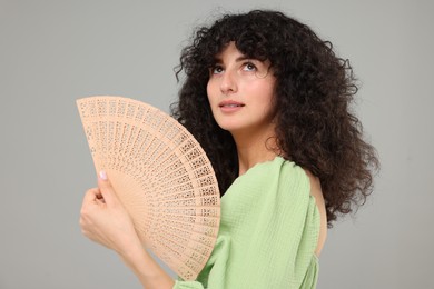 Photo of Woman holding hand fan on light grey background