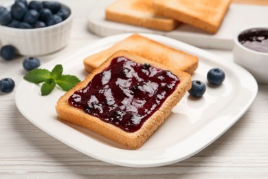 Photo of Toast with blueberry jam on white wooden table, closeup