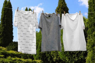 Photo of Washing line with clean clothes in garden. Drying laundry outside