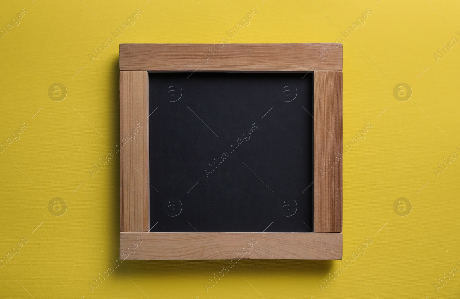 Photo of Blank chalkboard on yellow background, top view. Space for text