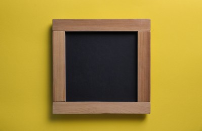 Photo of Blank chalkboard on yellow background, top view. Space for text