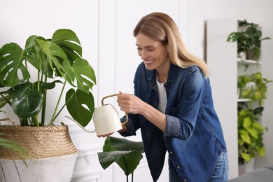 Photo of Woman watering beautiful potted houseplants at home