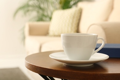 Photo of Cup of coffee and book on table in room