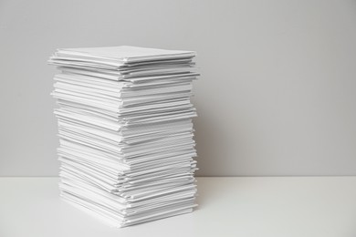 Photo of Stack of paper sheets on white table. Space for text